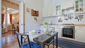 A modern kitchen with white cabinets, a gas stove, and various kitchen utensils hanging on the wall. - Rental in Rome Crociferi 1 (Rome)