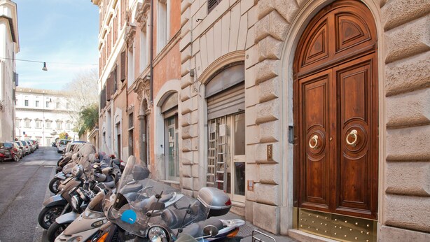 Uma fileira de motocicletas estacionadas em frente a um edifício com uma porta de madeira grande e uma janela pequena.