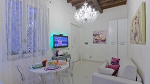 Uma sala de estar moderna com área de jantar, um candelabro e obras de arte nas paredes.