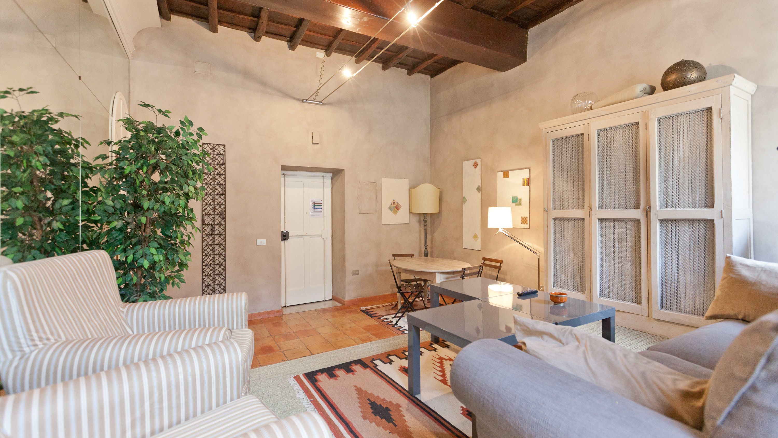 Una sala de estar con sofá, sillón, mesa de comedor y un ventanal con vistas.