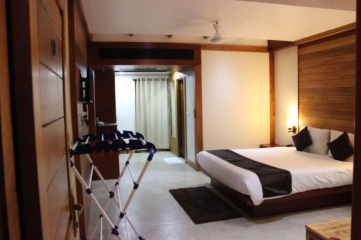 A hotel room with a bed, a wooden headboard, a nightstand, a bedside table, a ceiling fan, and a window with curtains.