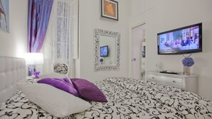 A bedroom with a bed, a television, a mirror, and a dresser.
