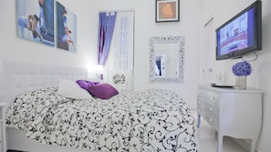 A bedroom with a bed, a dresser, a TV, and artwork on the walls. - Rental in Rome Parma (Rome)