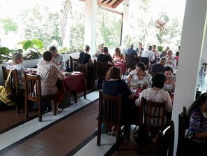 A restaurant with multiple tables and chairs, surrounded by greenery. - The Triangle Hotel (Anuradhapura)