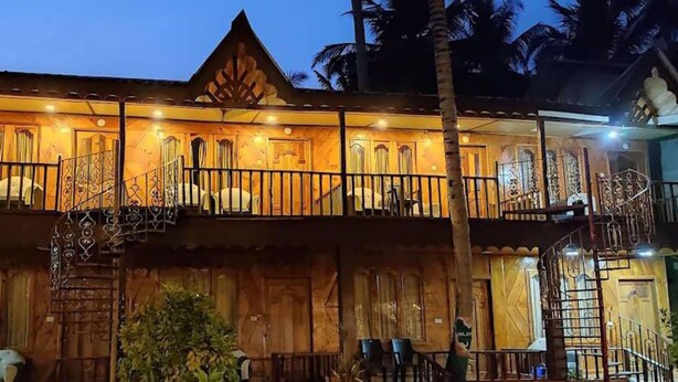 Un edificio de madera de dos pisos con balcones, una escalera y asientos al aire libre.