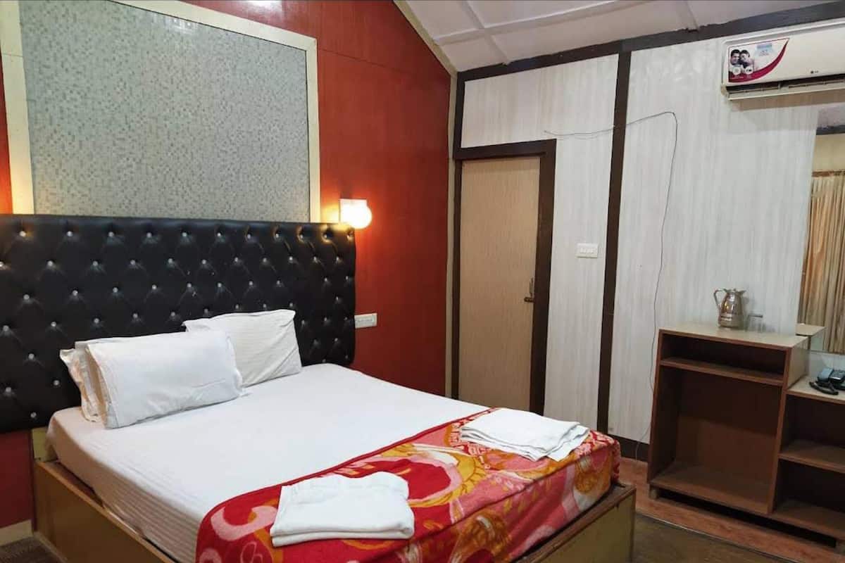 A hotel room with a bed, a wardrobe, and a desk.