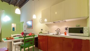 A compact kitchen with a dining area, a microwave, and a kettle. - Rental in Rome Crociferi 2 (Rome)
