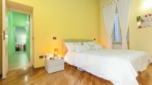Een slaapkamer met een bed, nachtkastje, lamp en een raam met gordijnen.