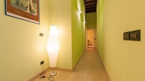A hallway with a lamp, a framed picture, and a door at the end. - Rental in Rome Crociferi 2 (Rome)