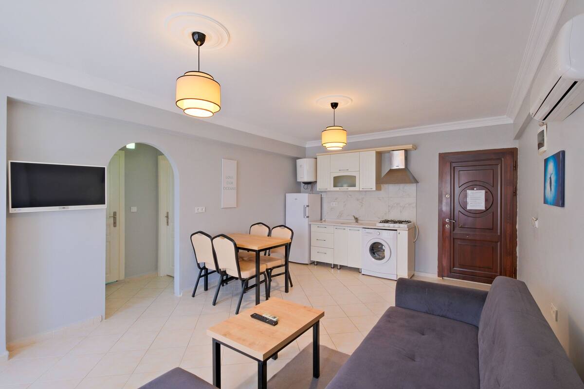 A compact living space with a dining area, kitchenette, and a sofa.