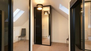 A narrow hallway with a skylight, a chair, and a door leading to another room. - The Townhouse (Derby)