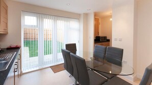 A modern kitchen with a microwave, a sink, and a countertop. There is a glass table with four chairs in the dining area. - The Townhouse (Derby)