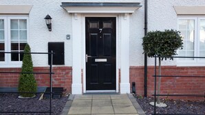 A white building with a black door, a small tree, and a metal fence. - The Townhouse (Derby)