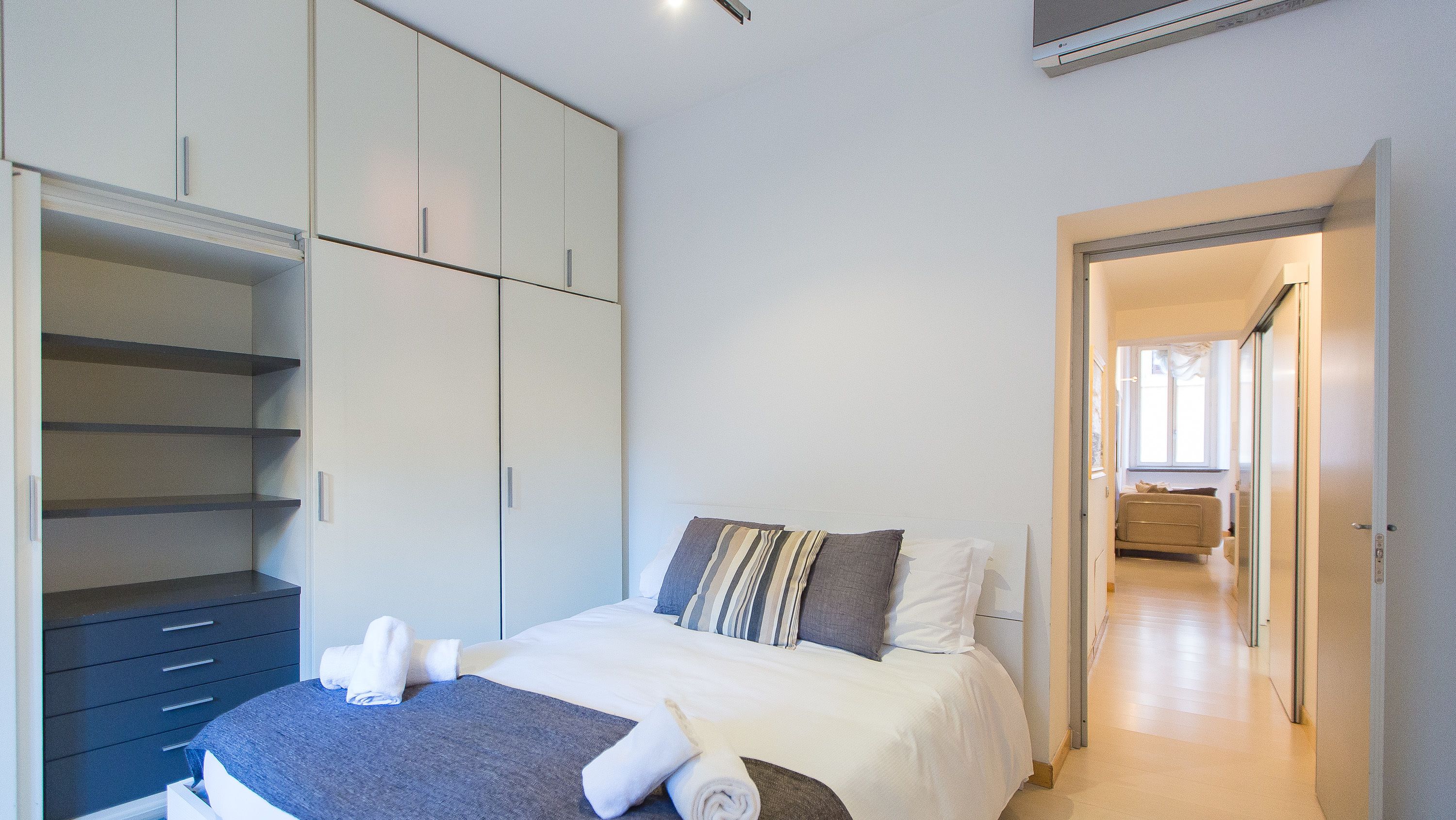 Ein Schlafzimmer mit Bett, Kleiderschrank und einem durchgegangenen Tür sichtbaren Badezimmer.