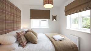 A bedroom with a bed, a window, and a radiator. - The Mews (Derby)