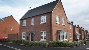 A two-story brick house with a dark roof, white-framed windows, and a front door. - The Mews (Derby)