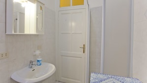 A bathroom with a white sink, a mirror, and a shower.