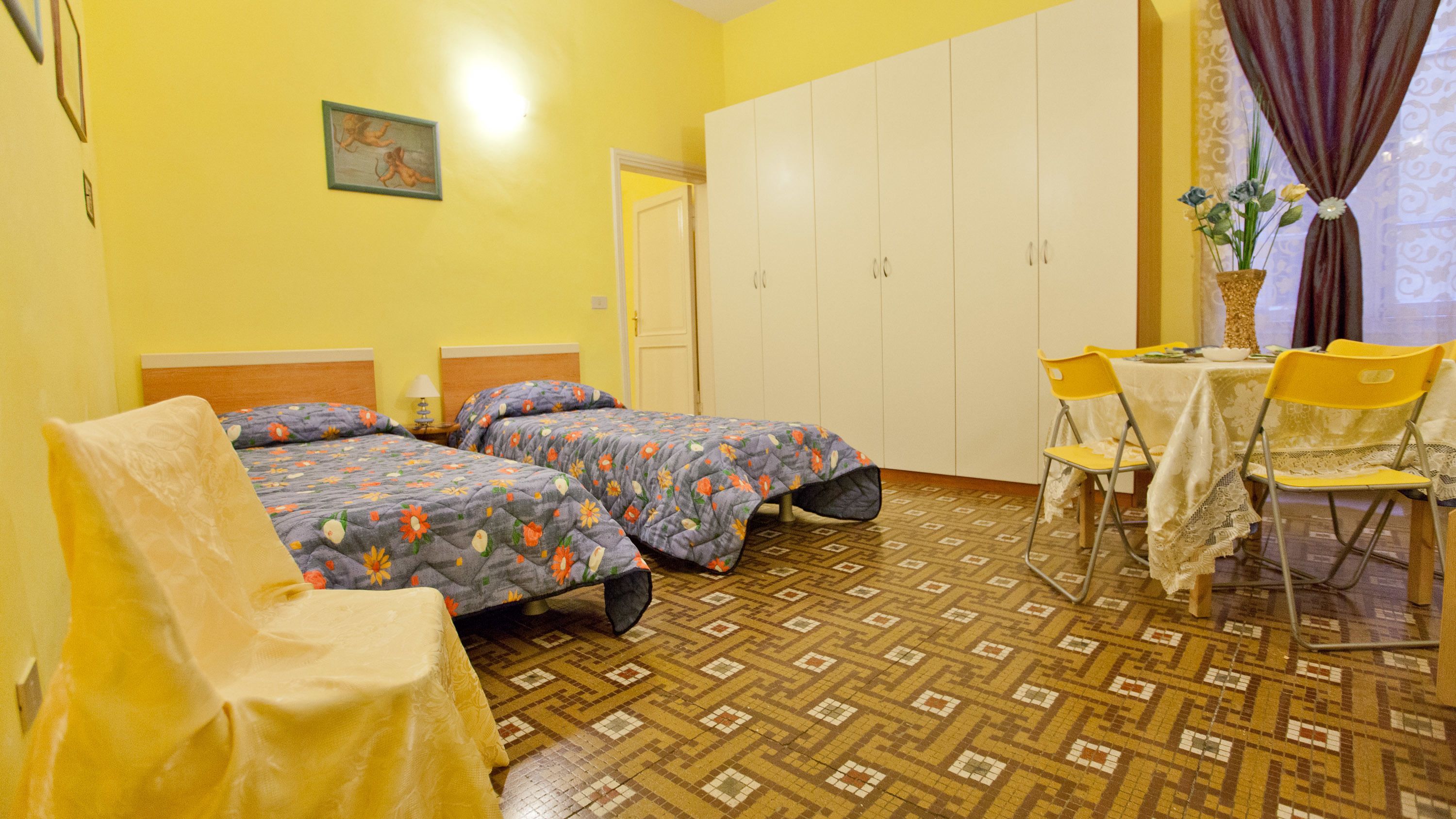 Une chambre avec deux lits, une chaise, une table et une armoire.