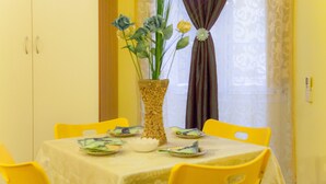 A dining table with yellow chairs, a vase with flowers, and plates with food.