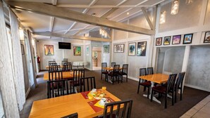 A dining area with multiple tables and chairs, a television mounted on the wall, and framed artwork on the walls. - Hotel de la Gare – urban by balladins (Chateauroux)
