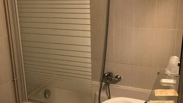 Un baño con ducha de vidrio, un lavabo blanco con espejo y un perchero para toallas.