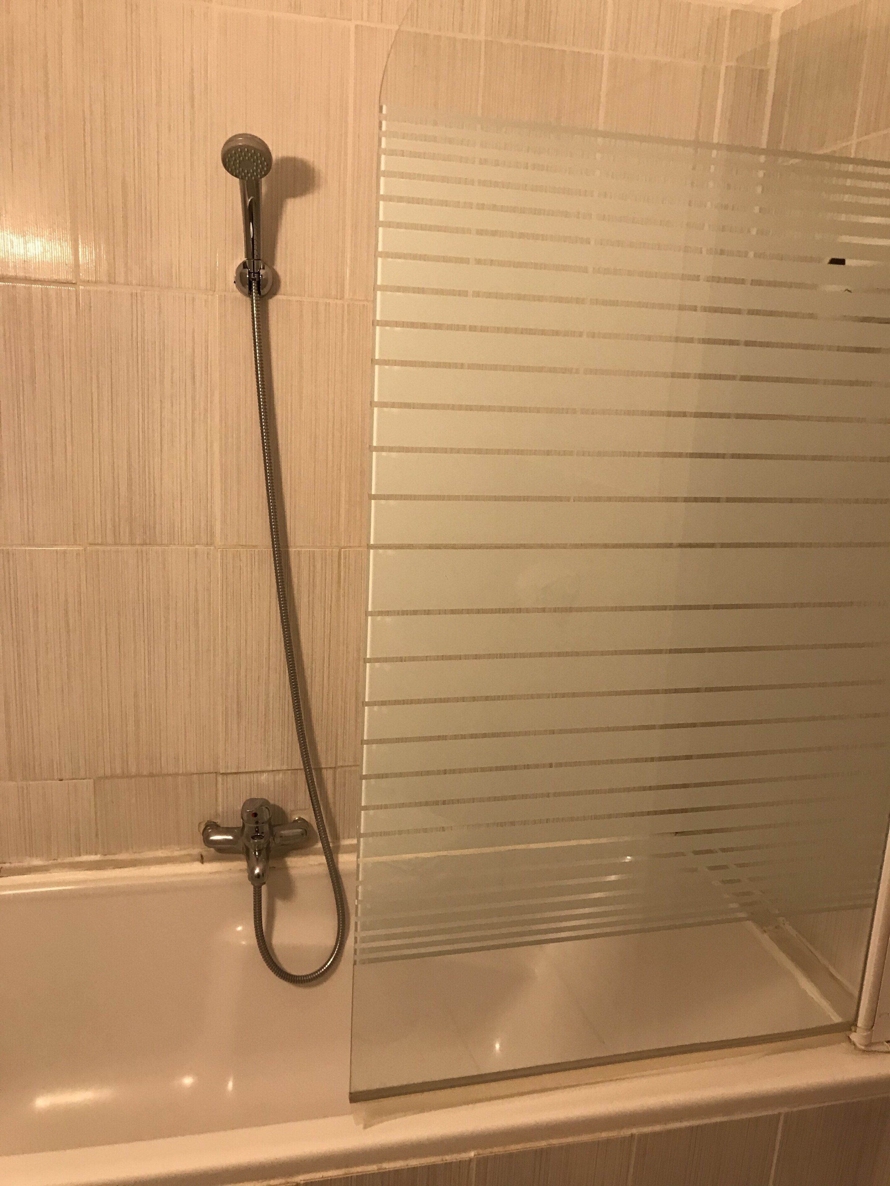 A shower enclosure with a glass door and a handheld showerhead.
