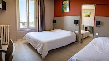Habitación de hotel con dos camas, un escritorio, una silla, un radiador y una ventana con vistas a edificios.