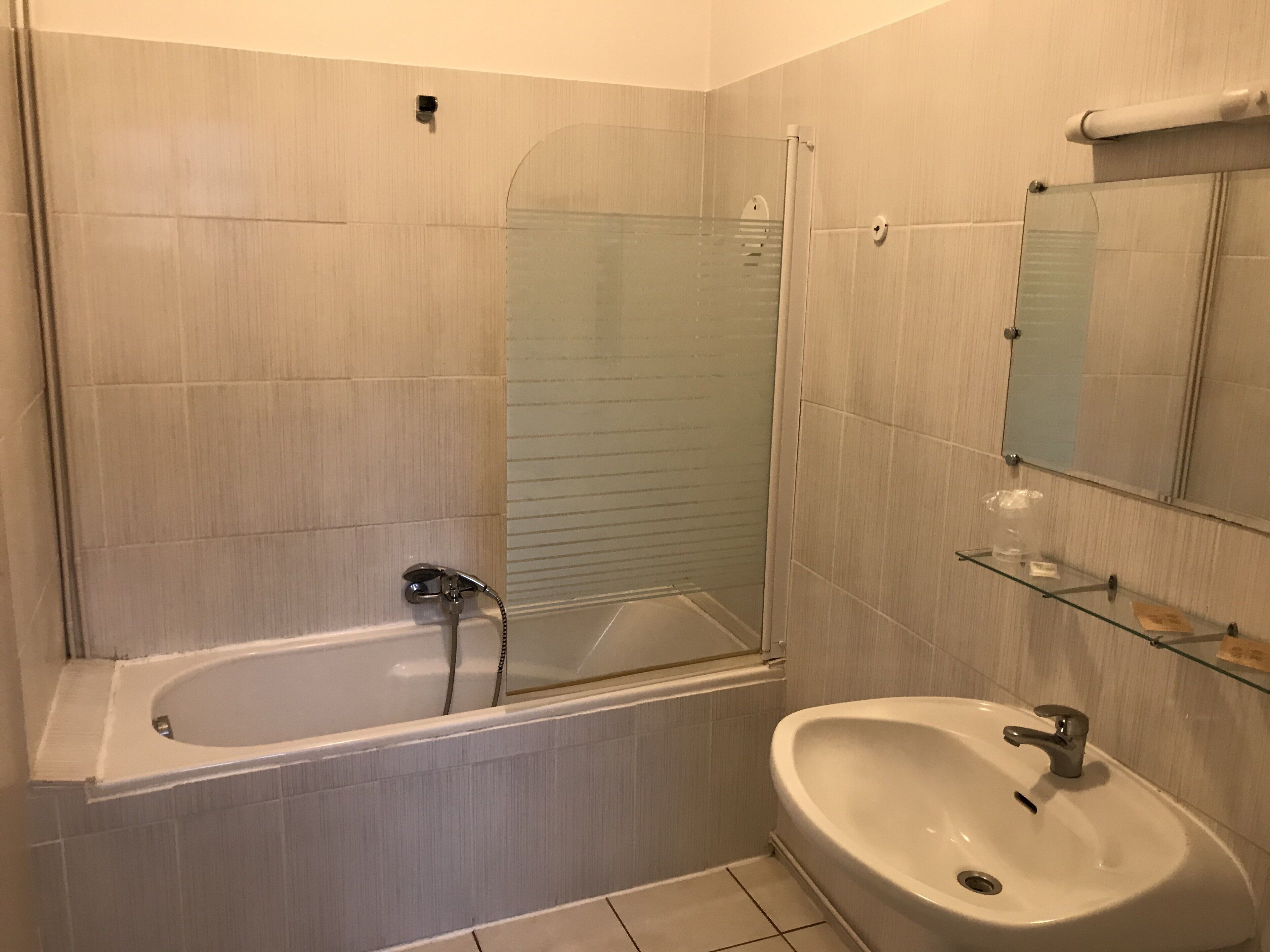 A bathroom with a bathtub, a sink, a glass shower enclosure, and a mirror.