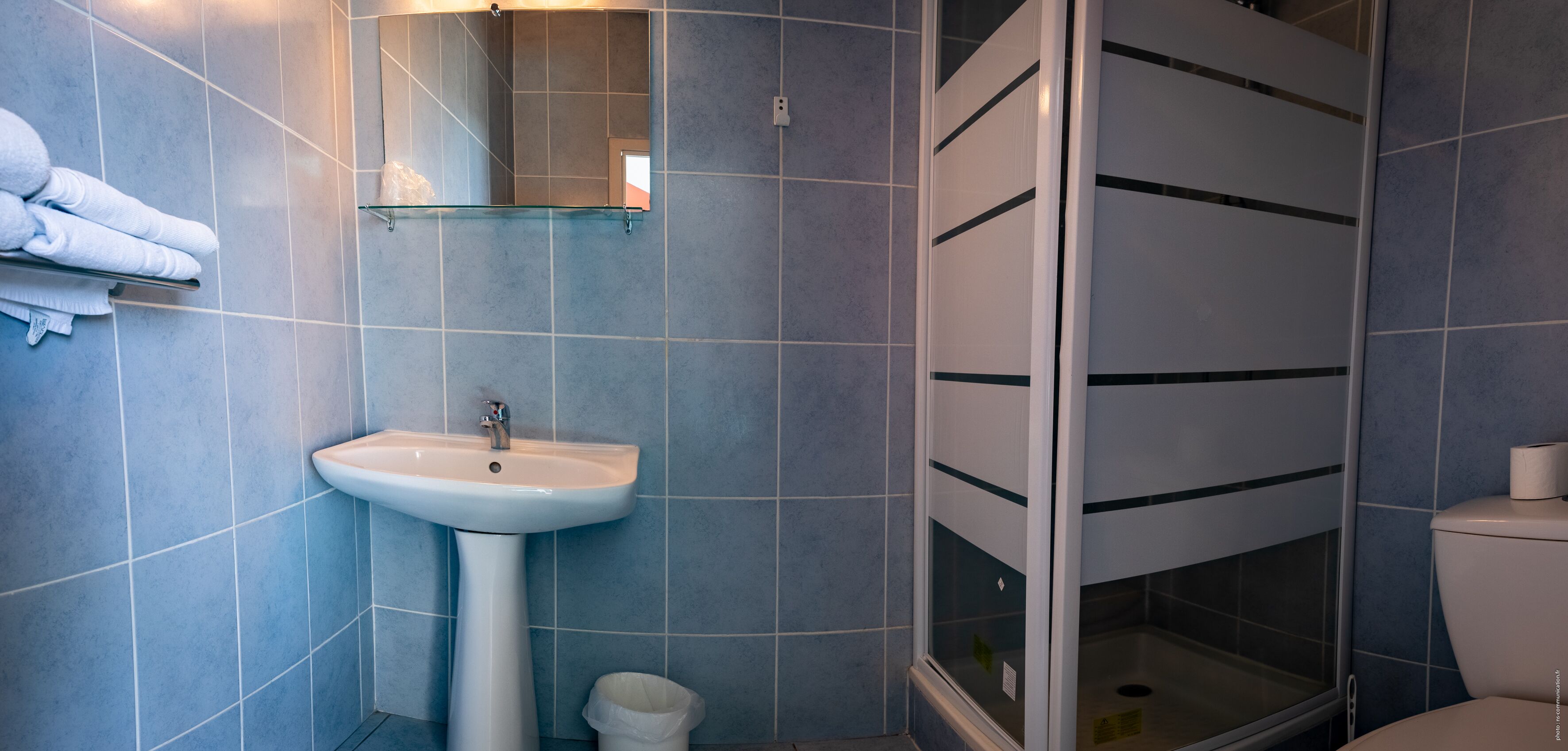 Ein Badezimmer mit einem weißen Waschbecken, einer Duschkabine aus Glas und einer Toilette.