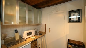 A kitchen with white cabinets, a microwave, a sink, and a wooden countertop. - Rental in Rome Romantica Studio (Rome)