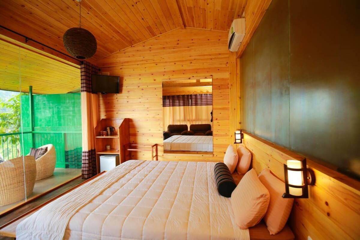 Une chambre dans un chalet en bois, comprenant un lit, un petit bureau, une chaise et un téléviseur.