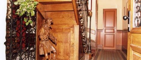 A wooden staircase with a metal railing, a wooden door, and a tiled floor.