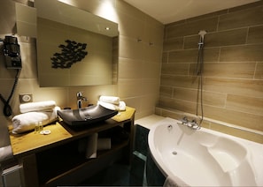 Un baño moderno con una bañera grande, un lavamanos con lavabo, un espejo y una ducha.