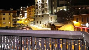 Vista nocturna de un edificio de varios pisos, con un balcón que tiene barandilla decorativa y un cartel que dice 'Glacier Sports'.