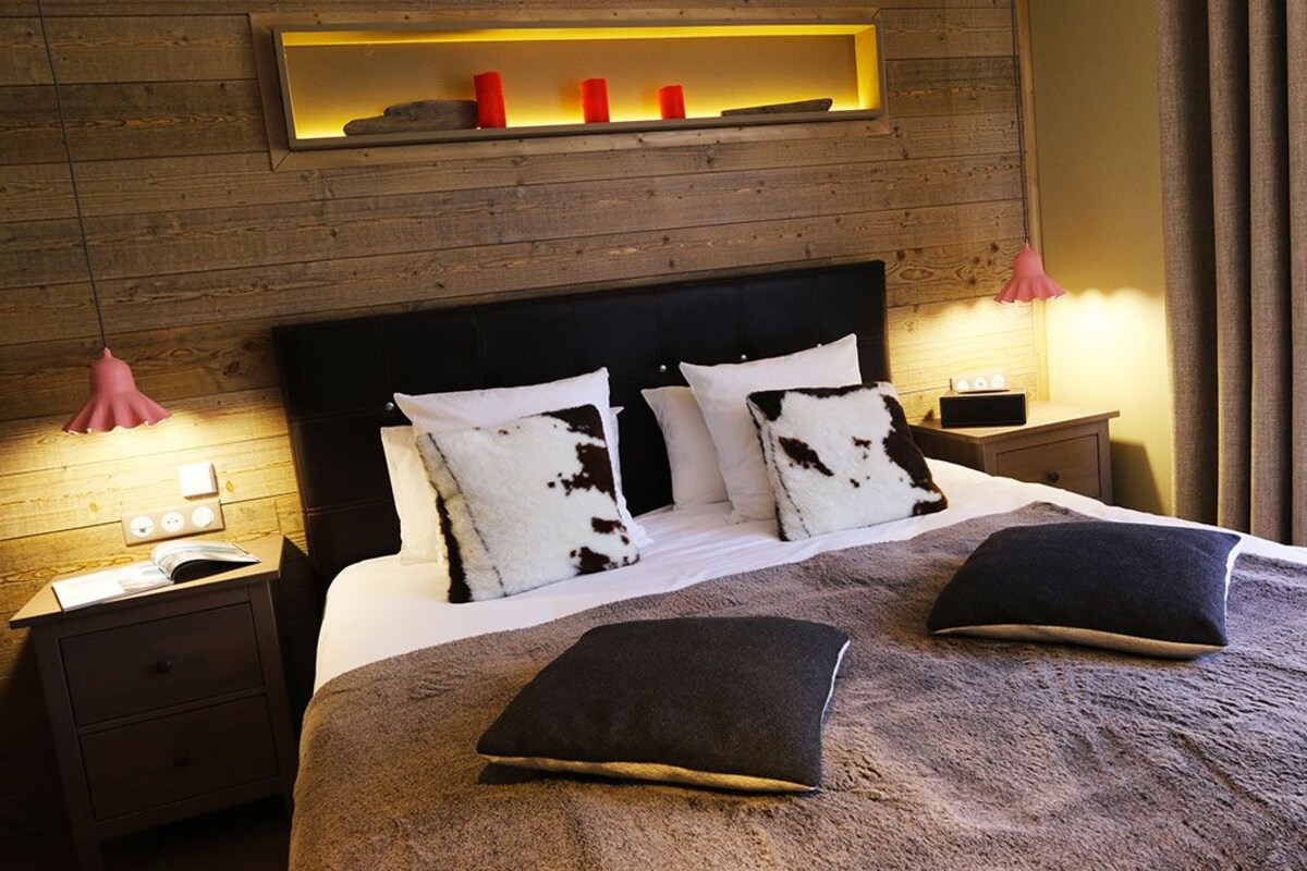 A bedroom with a wooden headboard, a bedside table with a lamp, and a shelf with candles.