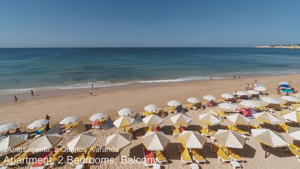 Uma praia com guarda-sóis e espreguiçadeiras.