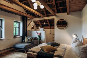 A bedroom with a loft bed, a small sofa, a bedside table with a lamp, and a window with curtains. - Berghütte Vogtland (Klingenthal)