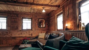 A cozy log cabin interior with a leather sofa, a small table with a vase of flowers, and a mirror on the wall. - Berghütte Vogtland (Klingenthal)