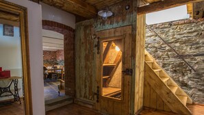 A rustic wooden staircase leading to a loft area with exposed brick walls and a wooden door. - Berghütte Vogtland (Klingenthal)