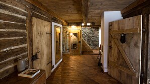 A rustic wooden hallway with a stone wall and a staircase leading to a loft. - Berghütte Vogtland (Klingenthal)