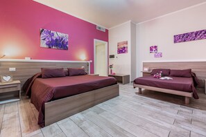 A bedroom with two beds, a wooden headboard, a bedside table with a lamp, and a wall-mounted artwork. -  ORCHIDEA HOUSE FIUMICINO two (Fiumicino)