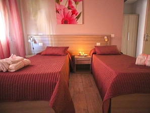 A hotel room with two beds, a nightstand with a lamp, and a painting on the wall. -  ORCHIDEA HOUSE FIUMICINO two (Fiumicino)