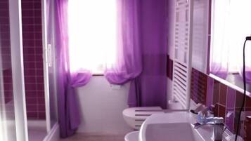 A bathroom with a white sink, a mirror, and purple curtains.