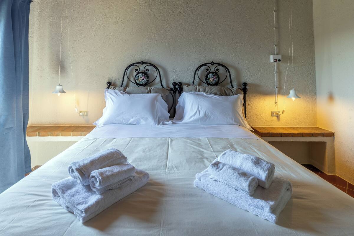Un lit bien fait, avec du linge de lit blanc et deux piles de serviettes pliées.
