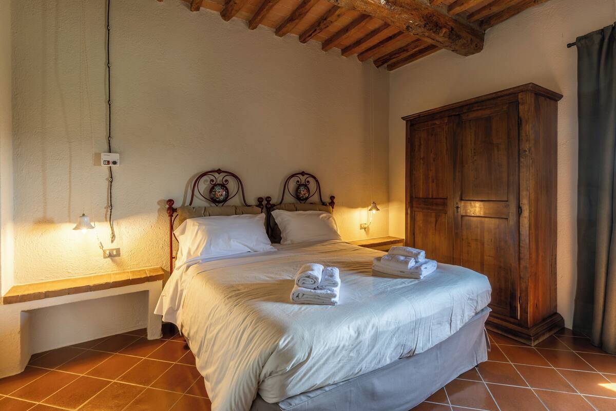 Une chambre à coucher avec un grand lit, une armoire en bois et un luminaire fixé au mur.