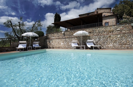 Una piscina al aire libre, sillones reclinables de piscina