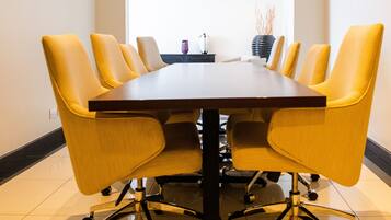 A conference room with a dark wooden table and yellow chairs.