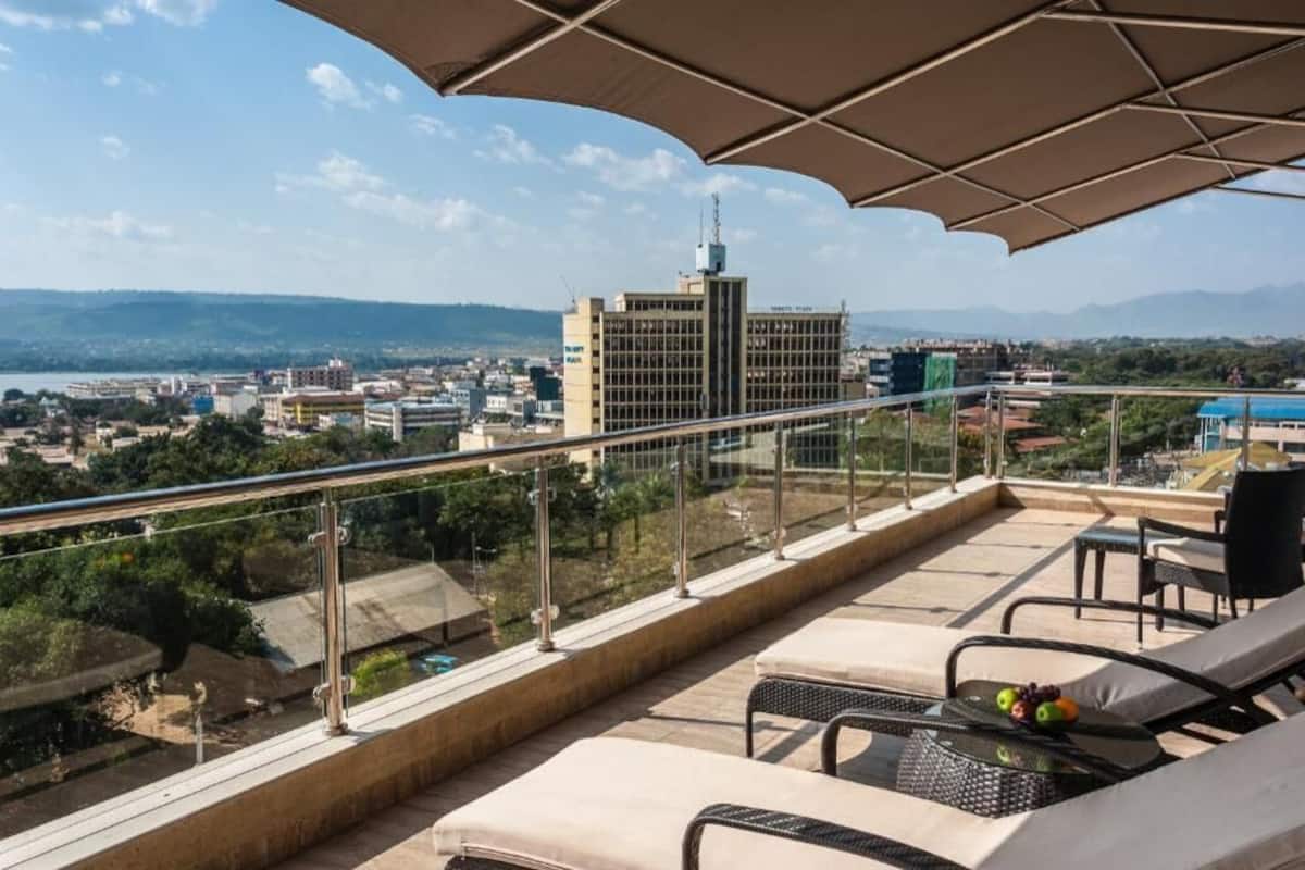 Ein Balkon mit Blick auf eine Stadtlandschaft, ein Tisch mit Früchten und ein Stuhl.