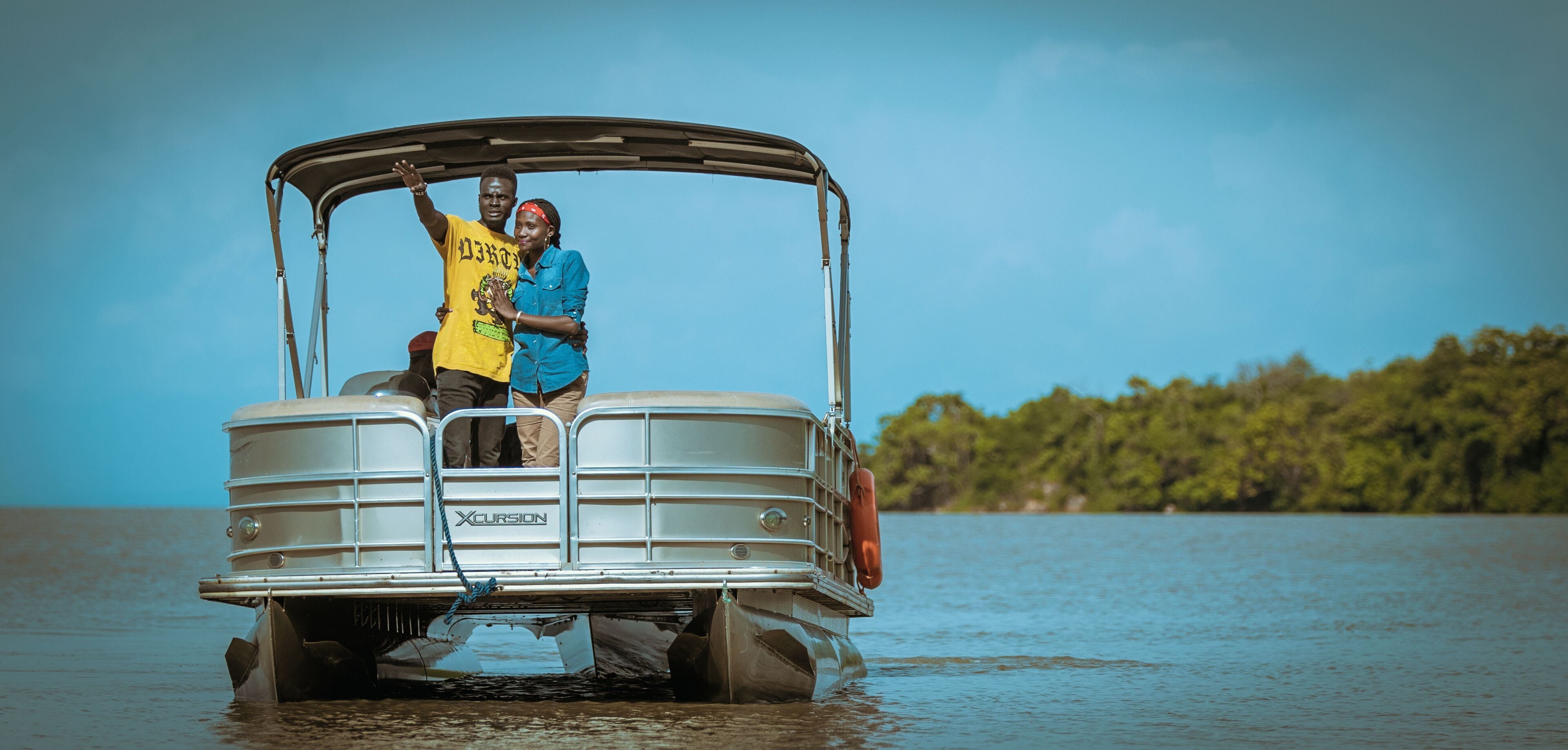 A boat with a metal frame and a canopy, equipped with a life buoy, floating on calm water.