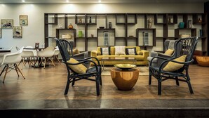 Un área de lounge moderna con sillas de mimbre, un sofá amarillo y una mesa de centro.
